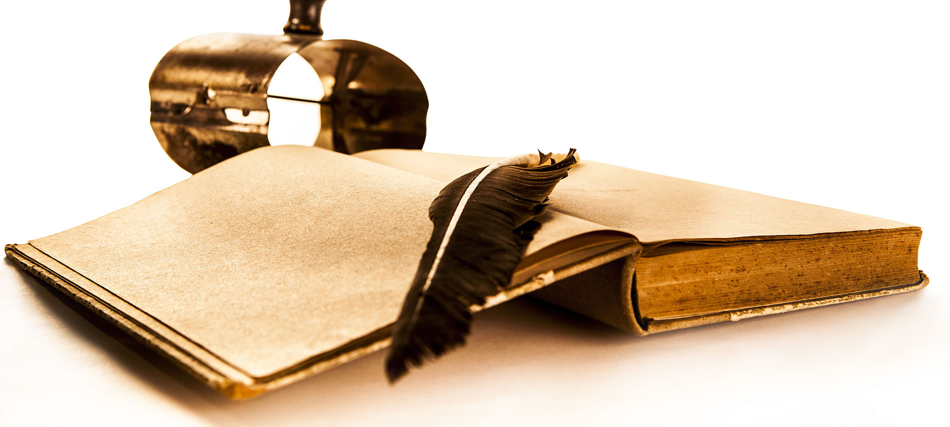 Open bound book with feather laying across pages, gold metal ink container.