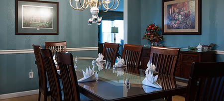 Teal painted dining room with framed prints, chandelier, view of living room through open door.