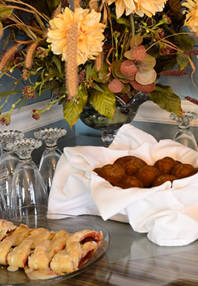 Raspberry danish on clear dish, mini muffins in napkin-lined basket, Vase of flowers.