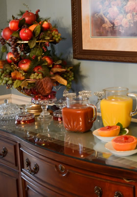 Cherry antique buffet with grapefruit halves with cherries, orange and tomato juice decanters, fruit bown with red apples.