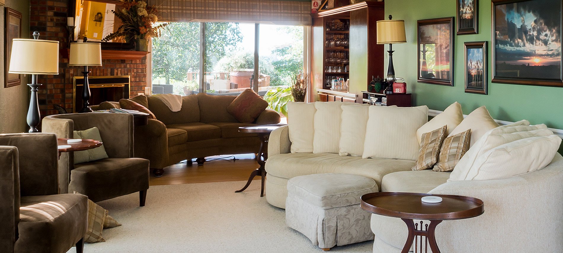 Brown suede couch and chairs, ivory couch, brick fireplace, large picture window, pictures on teal wall.